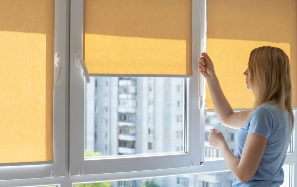 Woman Operating Yellow Roller Blinds